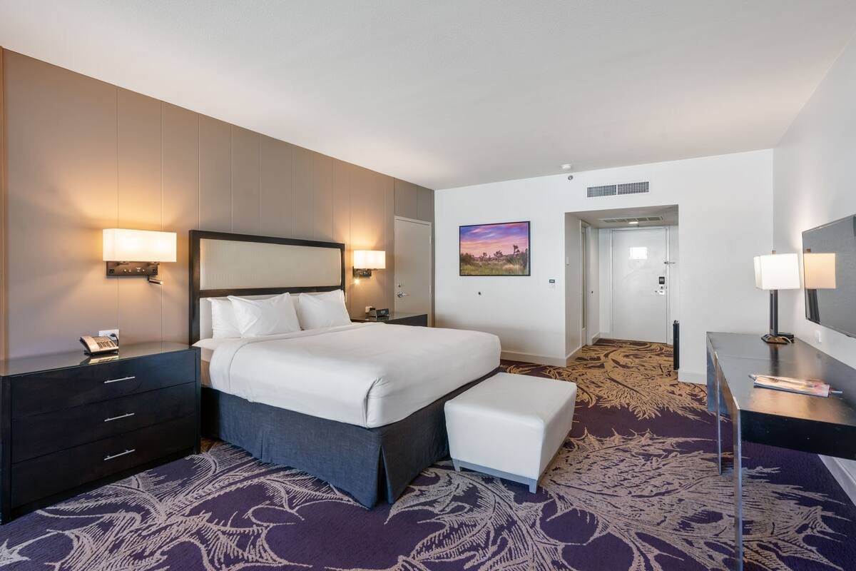 A hotel room with a large bed, bedside tables, a desk, and a chair.