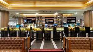 A bar area with leather seating, a bar counter with a variety of bottles, and a 'hotelzoso' sign. - Hotel Zoso (Palm Springs)