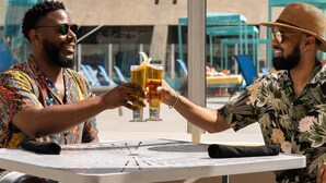 Two people toasting at a white table outdoors with a modern building in the background. - Hotel Zoso (Palm Springs)