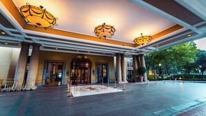 A grand entrance with a covered area, columns, and decorative lighting fixtures. - Palazzo Hotel (Sandton)