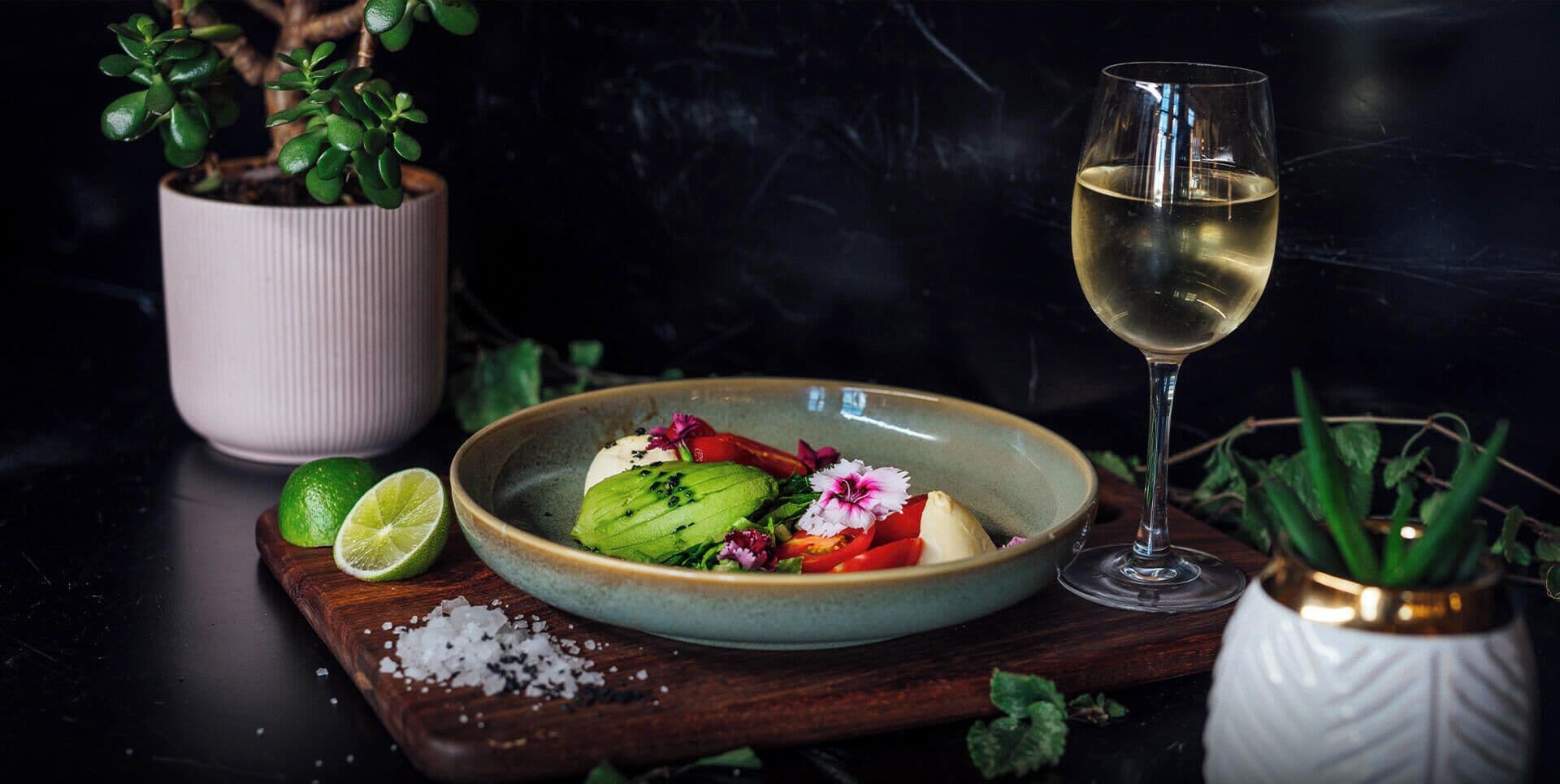 Eine Schüssel mit Essen, ein Glas Weißwein, eine halbe Limette und ein Holzbrett mit Salz.