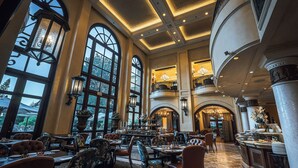 A spacious dining area with high ceilings, large windows, and elegant chandeliers. - Palazzo Hotel (Sandton)