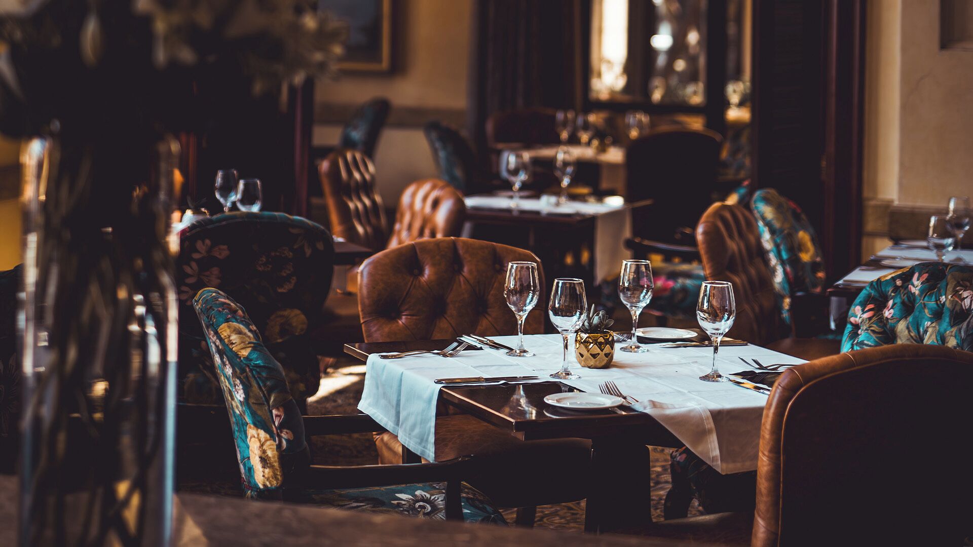 A restaurant interior with wooden tables, leather chairs, and a blue tablecloth.