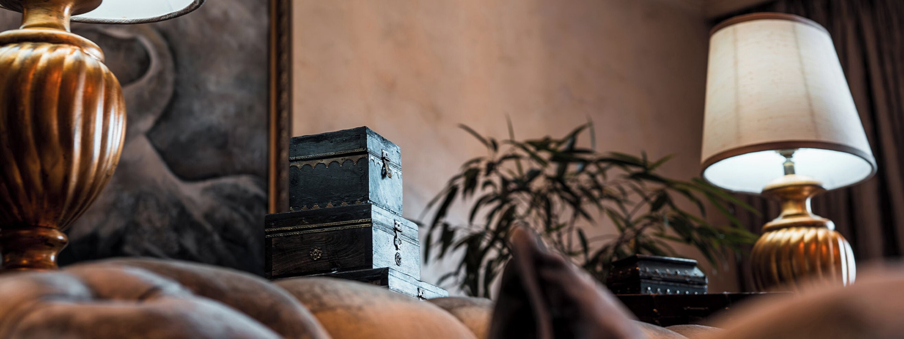 A close-up of a room with a lamp, a small wooden box, and a plant.