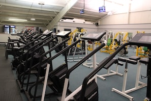A gym with treadmills, weight machines, and exercise mats.