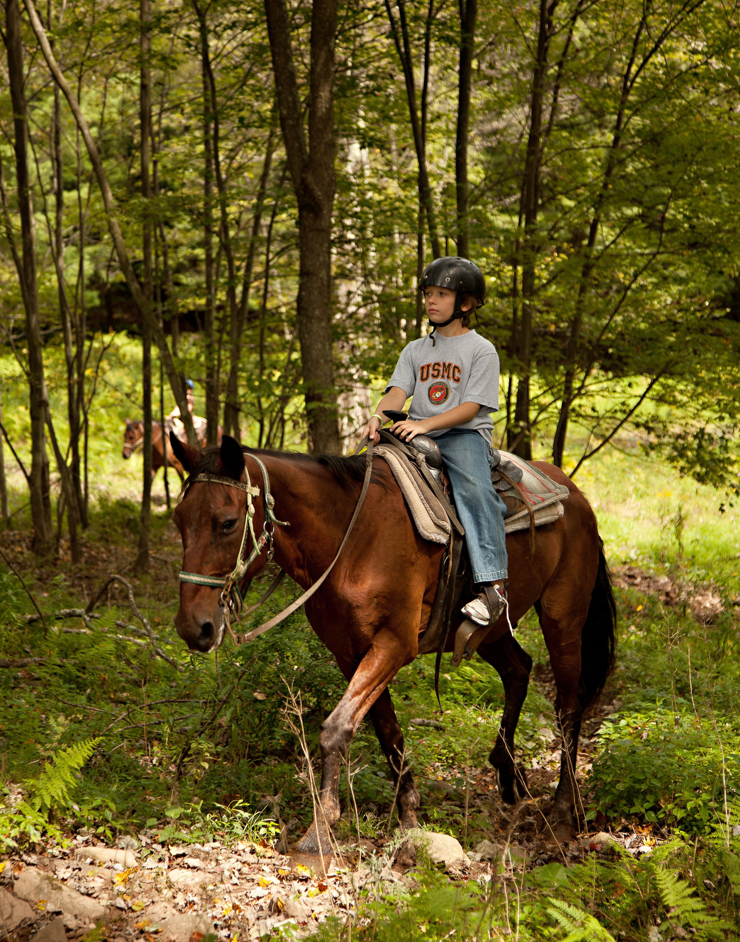 Un enfant à cheval dans une zone boisée.