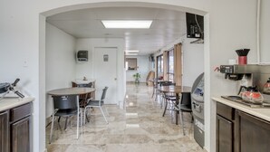 Una cocina moderna con una isla central, un comedor con sillas y un microondas.