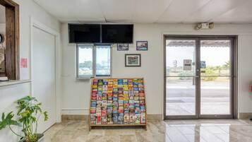 A reception area with a display of travel brochures, a television mounted on the wall, and a door leading outside.