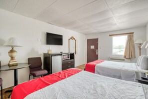 A hotel room with two beds, a desk, a chair, a TV, a mirror, and a window with curtains. - Lackland Gateway Inn (San Antonio)