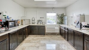 Una cocina con armarios de madera oscura, microondas, cafetera y ventana con vista al exterior.