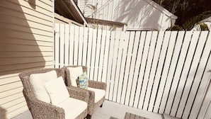 A patio with wicker furniture and a small table, enclosed by a white fence. - The Independent Inn - Formerly Heron House Court  (Key West)