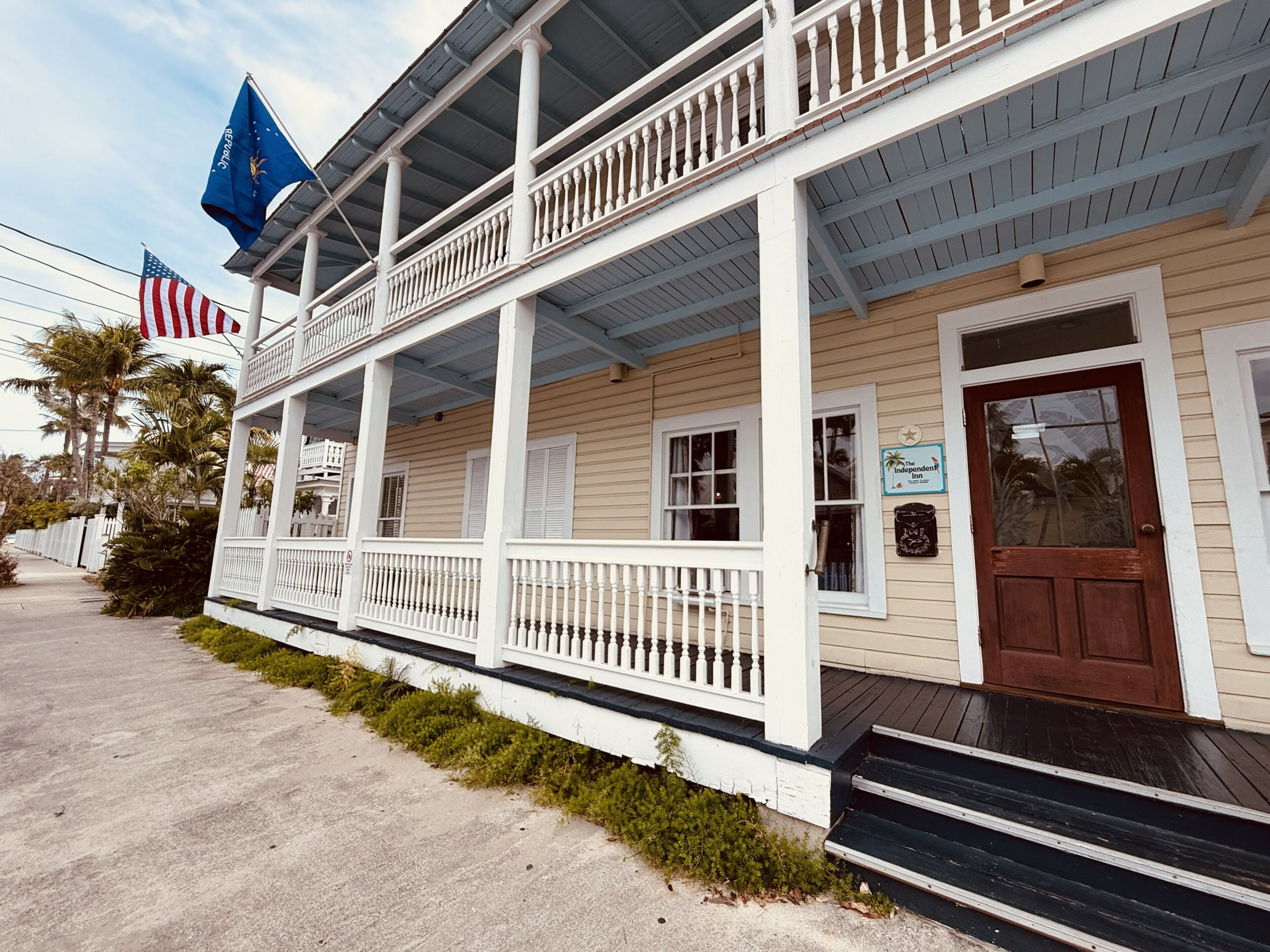 A two-story building with a porch, a brown door, and a sign for 'The Independent Inn'.