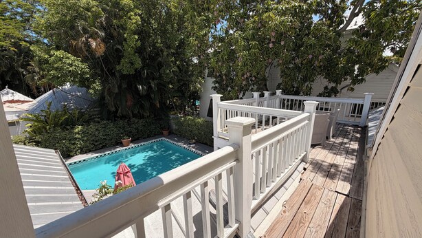 A pool surrounded by lush greenery and a wooden deck. - The Independent Inn - Formerly Heron House Court  (Key West)