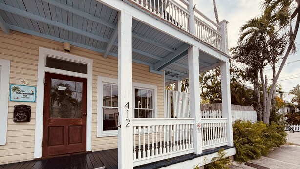 A two-story building with a porch, a front door, and a mailbox. - The Independent Inn - Formerly Heron House Court  (Key West)