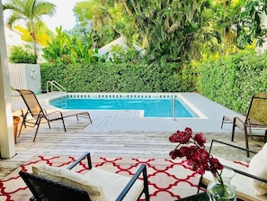 Una piscina al aire libre, sombrillas, sillones reclinables de piscina