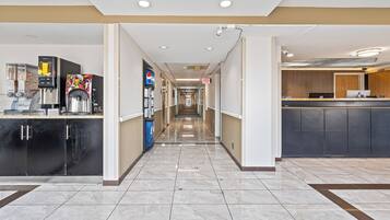 A hotel corridor with a coffee station, a Pepsi refrigerator, and a reception desk.