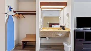 A bathroom with a sink, mirror, towel rack, and a television.