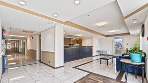 A spacious lobby with a modern design, featuring a reception desk, seating area, and a view of the outside.