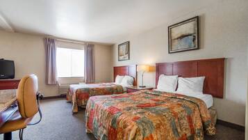 A hotel room with two beds, a desk, a chair, a television, and a painting on the wall.
