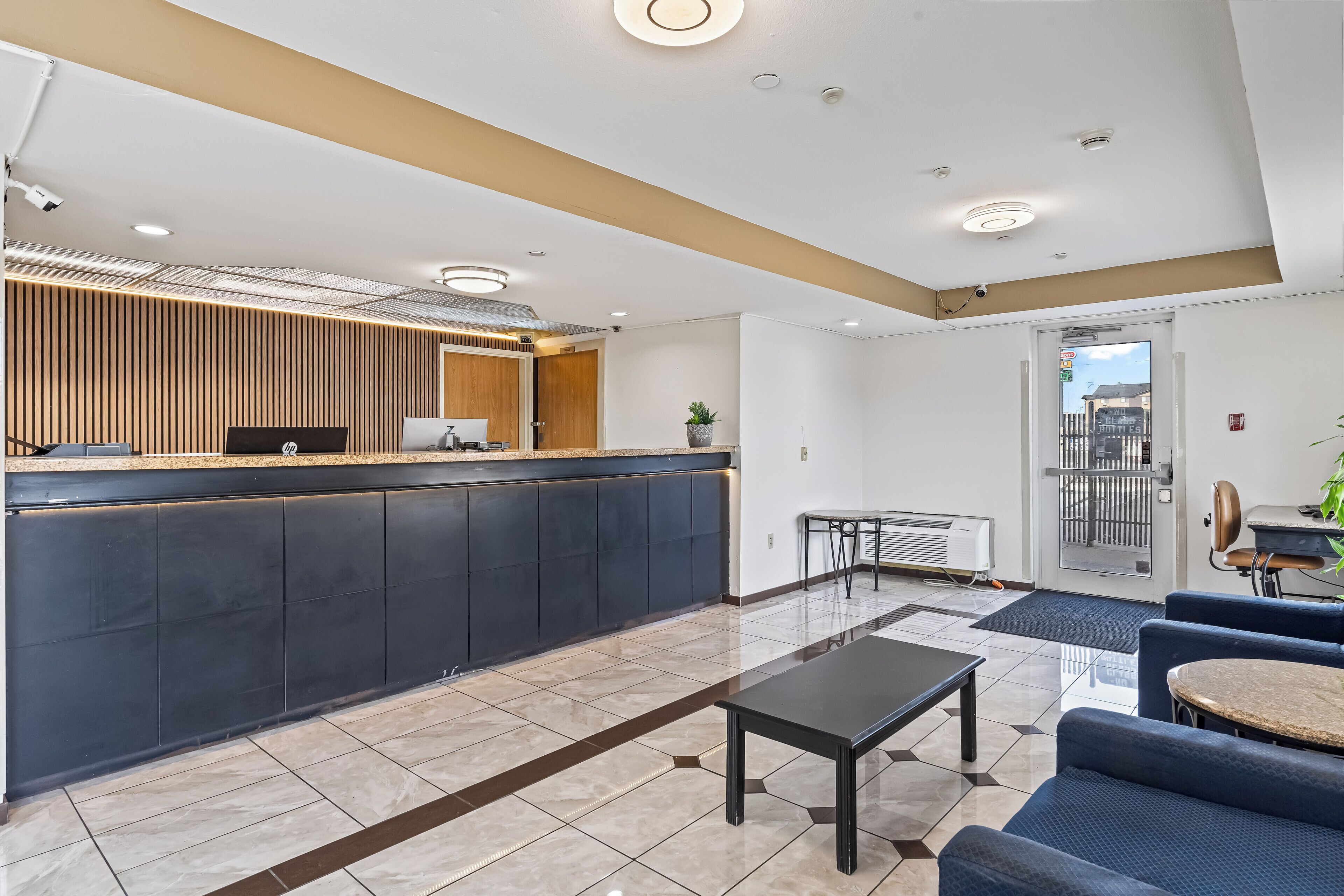 A modern hotel lobby with a reception desk, seating area, and a view of the outside.