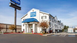 A hotel with a sign reading "Rodeway Inn & Suites," featuring a traditional architectural style with a blue roof and white exterior walls.