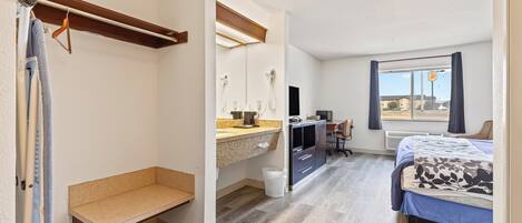 A bedroom with a bed, a desk, a chair, and a bench.
