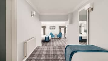 Una habitación de hotel con una cama, dos sillas, una mesita y un espejo.