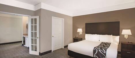 A hotel room with a large bed, two bedside tables with lamps, a wardrobe, and a door leading to a closet.