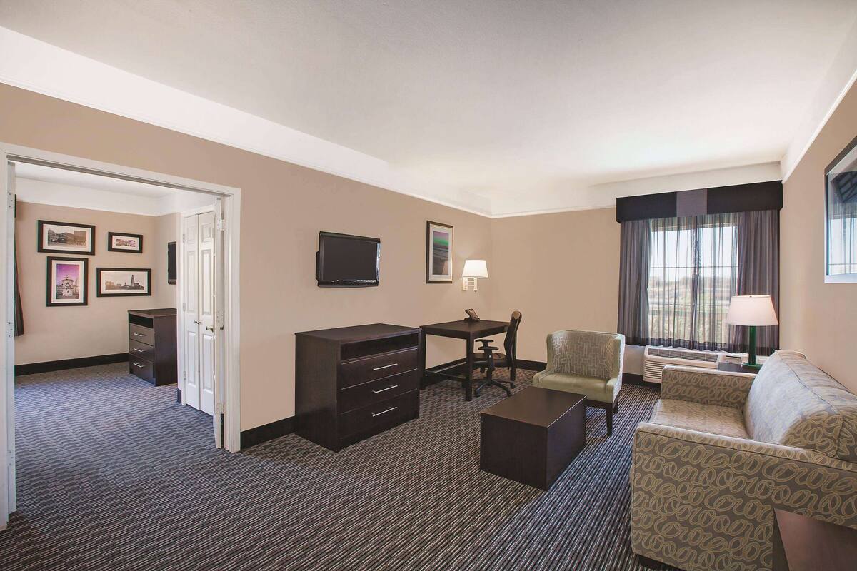 Een hotelkamer met een bureau, stoel, bank en een televisie.