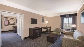 Una habitación de hotel con escritorio, silla, sofá y televisor.