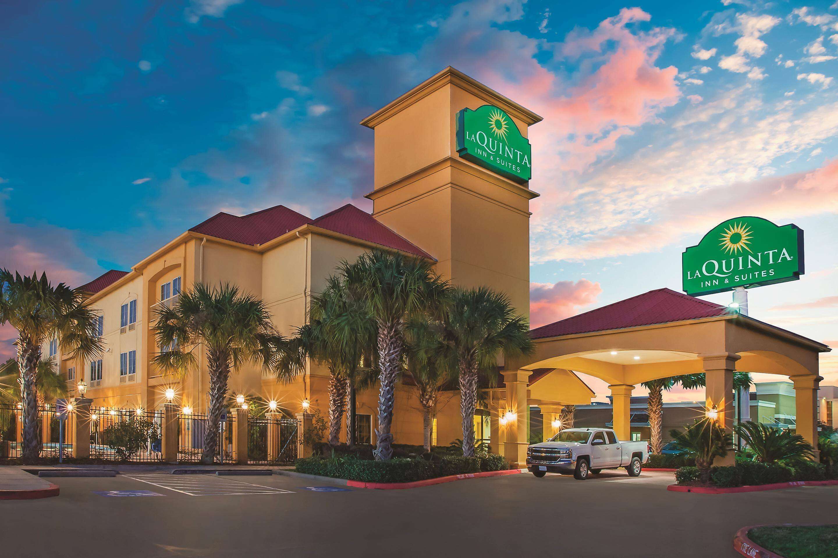 A hotel with a prominent sign, a parking lot, and palm trees.