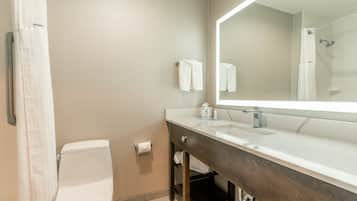 Un baño con inodoro, lavamanos, espejo y cortina de ducha.