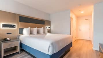 A modern hotel room with a large bed, bedside tables, and a built-in desk.