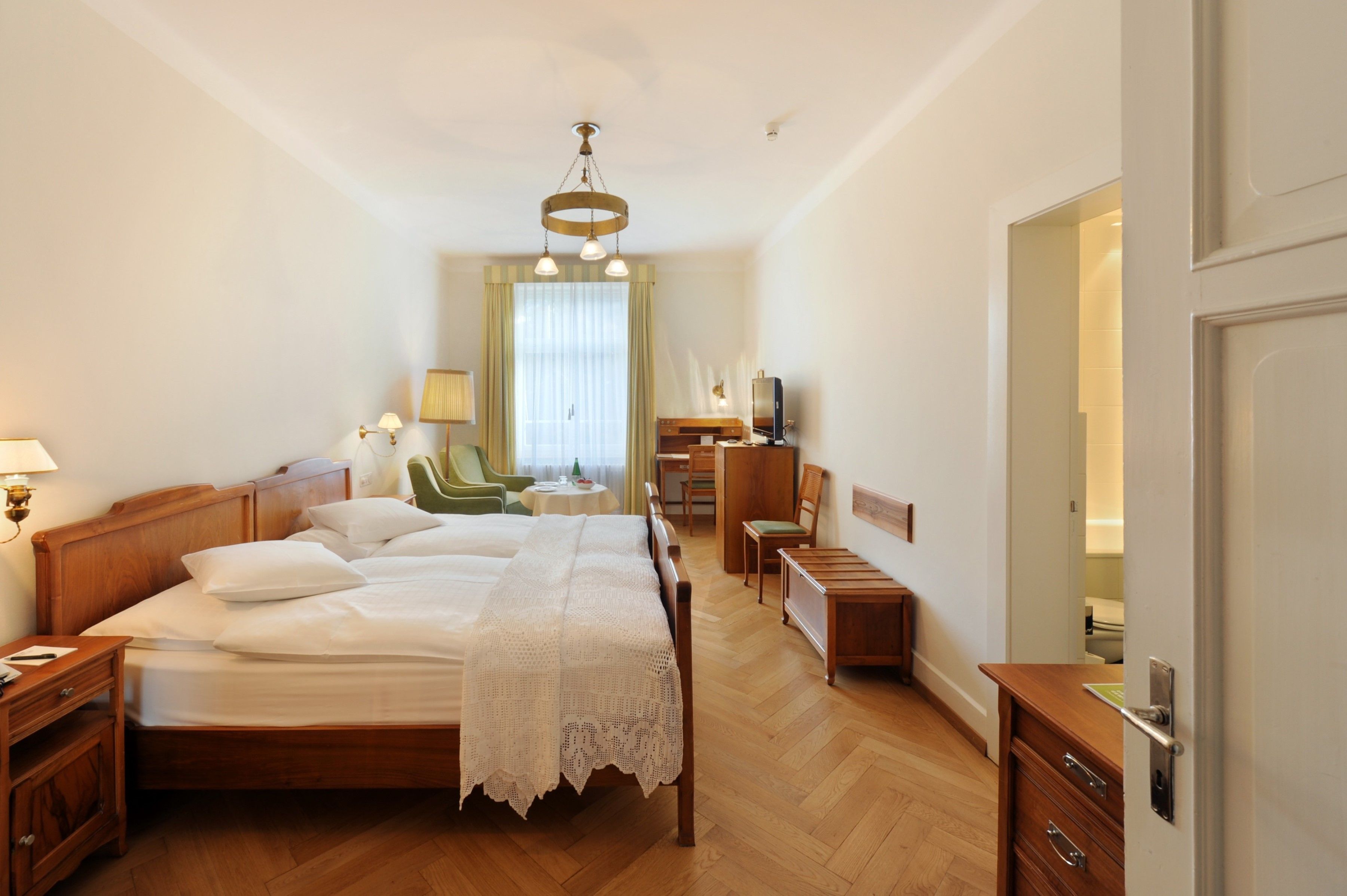 Un cuarto de hotel ordenado con una cama grande, mesitas de noche, un escritorio y una silla.