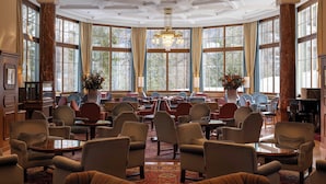Eine geräumige Lobby mit großen Fenstern, bequemen Sitzgelegenheiten und einem Kronleuchter.