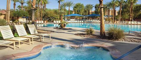 A pool area with lounge chairs and palm trees.