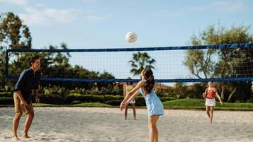 A beach volleyball game in progress with a net and players.