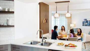 Eine moderne Küche mit einer zentralen Kochinsel, Edelstahlgeräten und einem Essbereich mit Tisch und Stühlen.