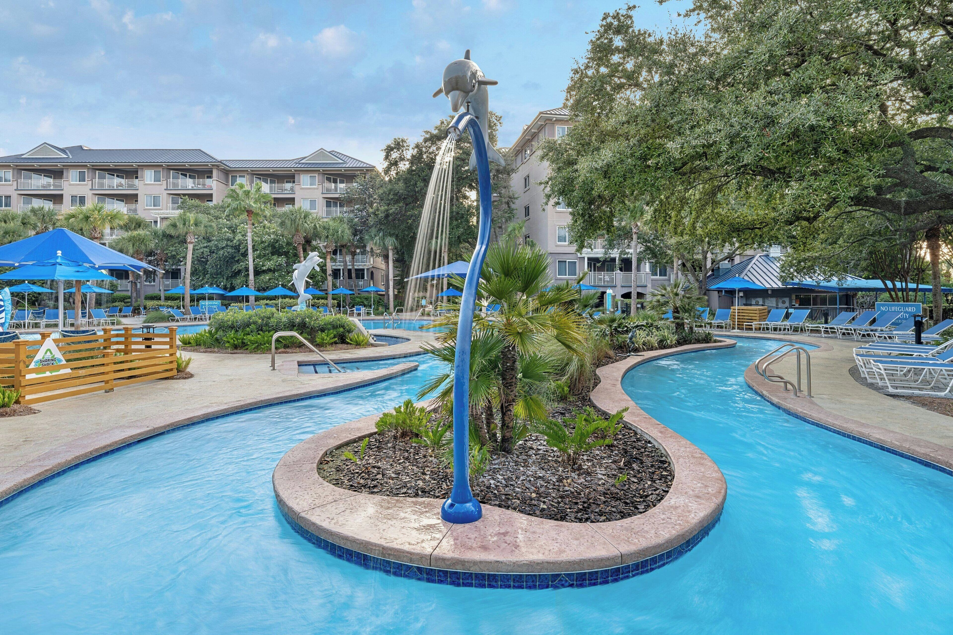 A swimming pool with a dolphin statue, lounge chairs, and a no swimming sign.