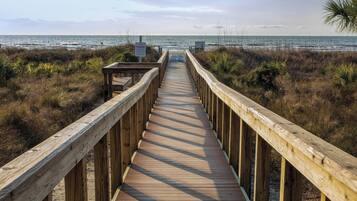 Un paseo marítimo de madera que conduce a la playa, con un letrero que indica 'Private Beach'.