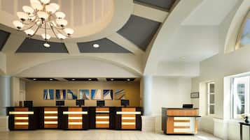 A reception area with a modern design, featuring a reception desk, artwork on the wall, and a chandelier.