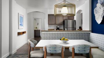 Une cuisine moderne avec un coin repas, comprenant une table blanche, des chaises à motifs bleus et un luminaire suspendu.