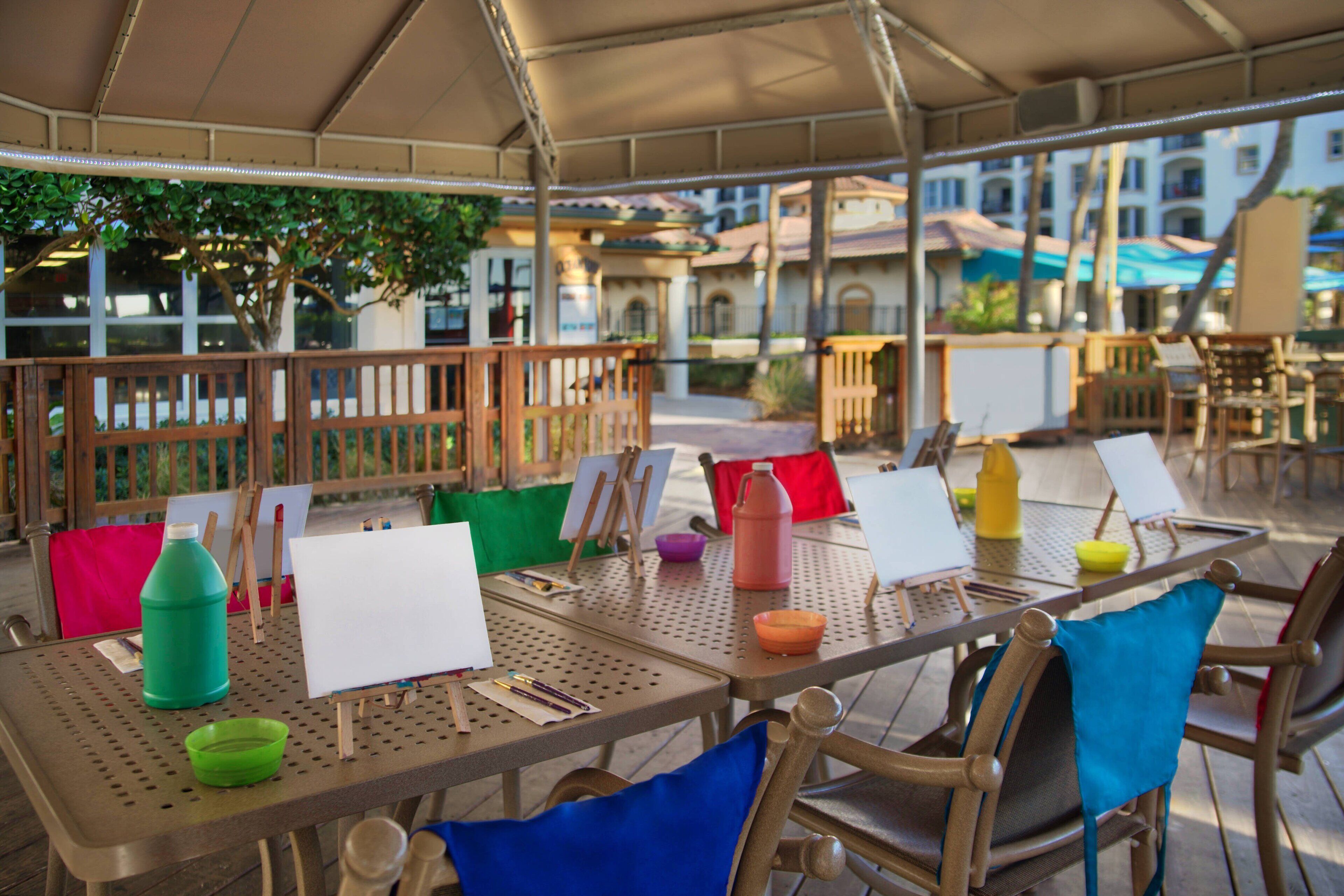 Un espacio de comedor al aire libre con mesas, sillas y diversos utensilios para comer.