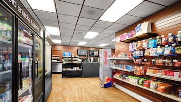 Interior de un supermercado con secciones refrigeradas, un refrigerador de Red Bull y estantes llenos de aperitivos y bebidas.