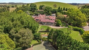 A large estate with a main house surrounded by lush gardens and a tennis court. - Peppers Manor House (Sutton Forest)