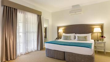 Habitación de hotel con una cama grande, dos lámparas de noche, una mesita de noche y una ventana con cortinas.