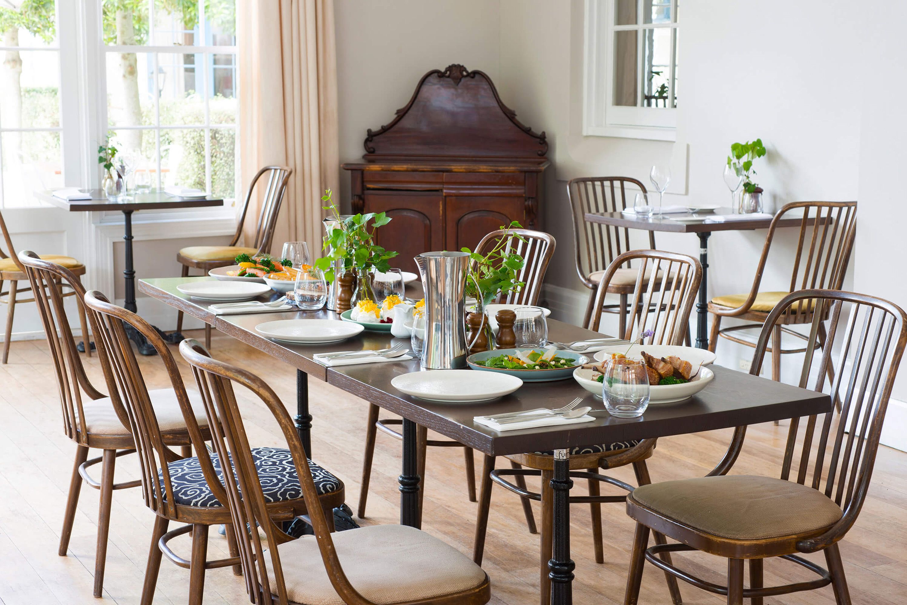 A dining room with a long table set for six, surrounded by wooden chairs with cushioned seats.