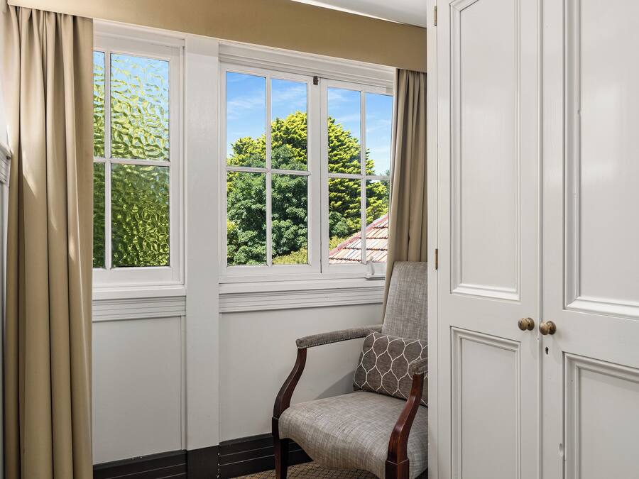 Una habitación con ventana, una silla y una puerta.