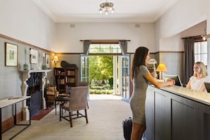 A reception area with a desk, chairs, and a view of the outdoors. - Peppers Manor House (Sutton Forest)