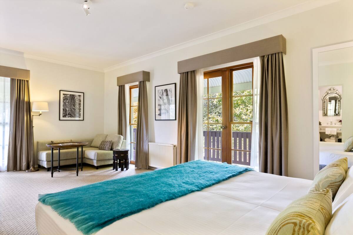 Habitación de hotel con una cama grande, un sofá, una mesita y vistas al exterior.